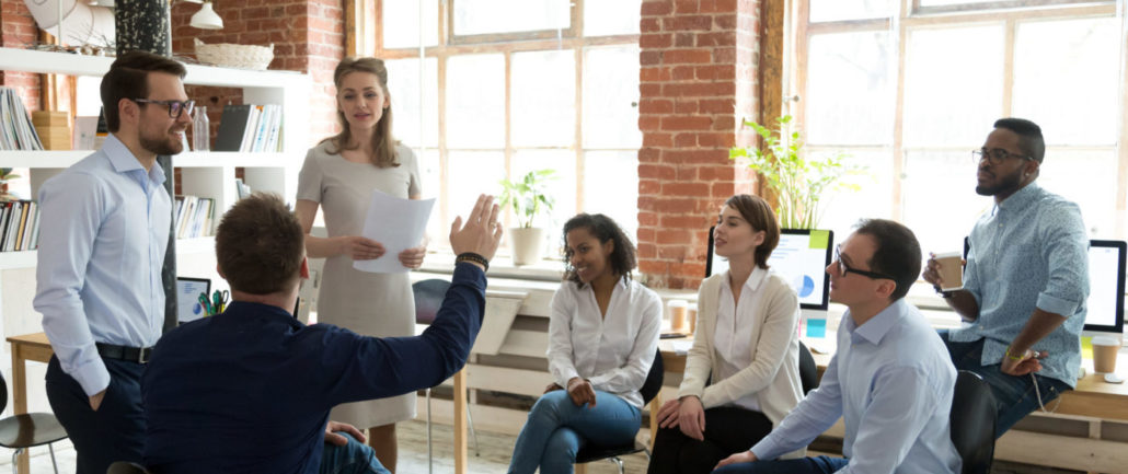 Male worker raise hand asking question at office teambuilding
